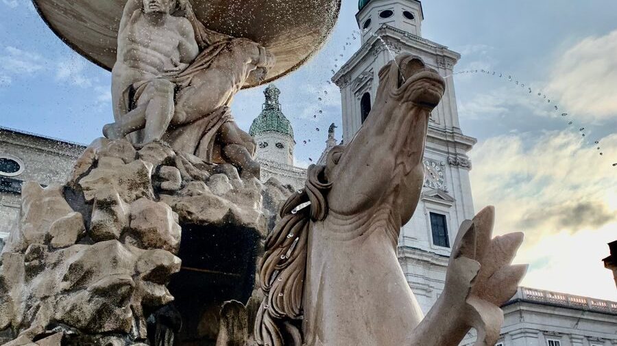 Majestic baroque fountain with sculptures at sunrise in Salzburg Residenzplatz.