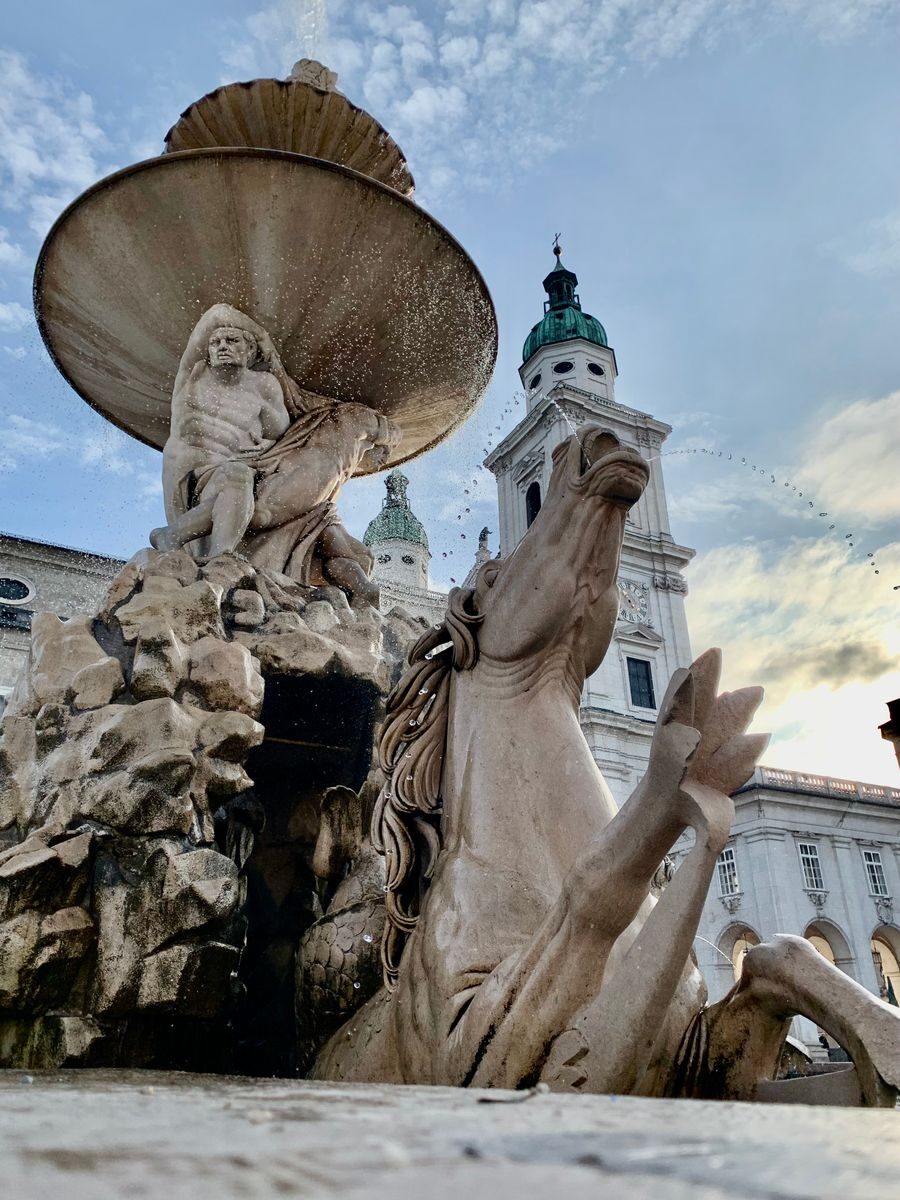 Majestic baroque fountain with sculptures at sunrise in Salzburg Residenzplatz.