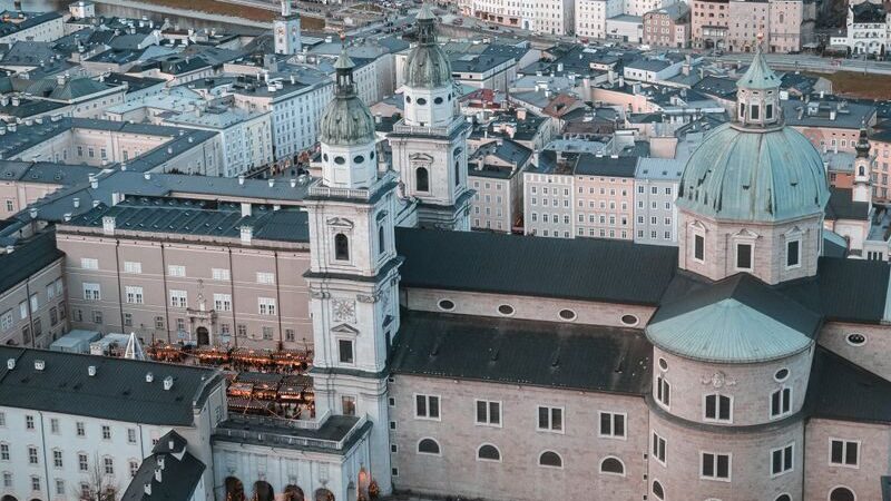 Photo by Enis Mehmeti Stunning aerial view of Salzburg Cathedral amidst the cityscape, capturing urban vibrancy.