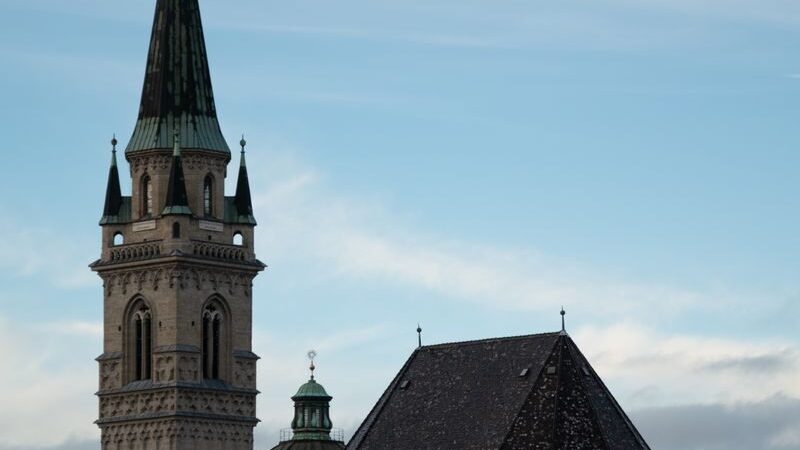 Stunning vertical shot of a Gothic church tower under a cloudy sky in Salzburg, Austria.