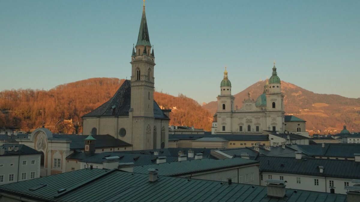 Scenic skyline of Salzburg featuring historic churches and rooftops at sunset.