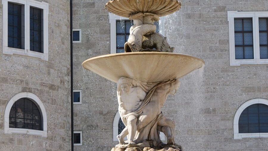 Photo by David Magauer Elegant Baroque-style fountain in Salzburg featuring intricate stone sculptures and water spray.