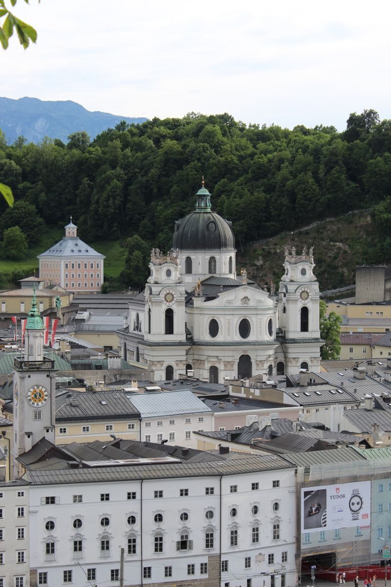 A scenic view of Salzburg Cathedral with surrounding buildings and lush greenery.