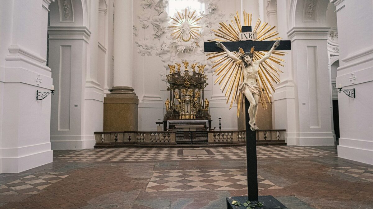 Photo by Free Walking Tour Salzburg gold and black cross on white concrete building
